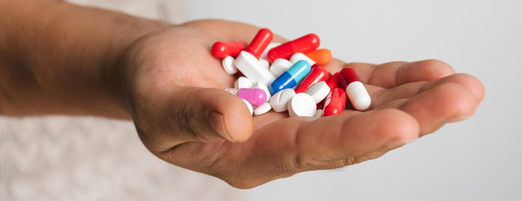Close-up of a person holding assorted colorful pills and capsules, symbolizing misconceptions about natural supplements not interacting with other medications.