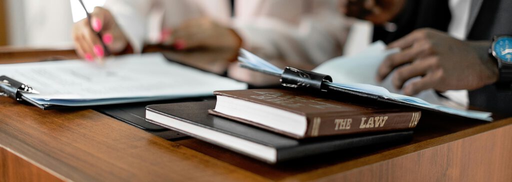 Close-up of law books and documents on a desk with professionals reviewing papers, symbolizing legal frameworks and regulatory compliance in the global sleep supplement industry.